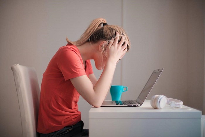 Woman in red t-shirt looking at her laptop